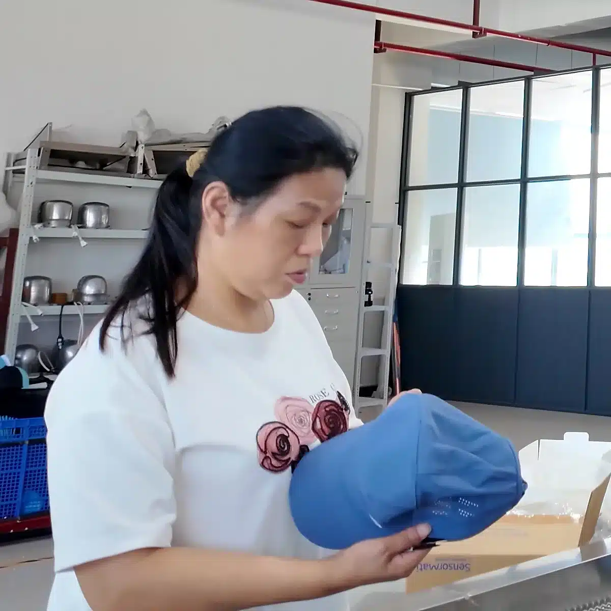Worker reviewing the shape of a blue baseball cap sample