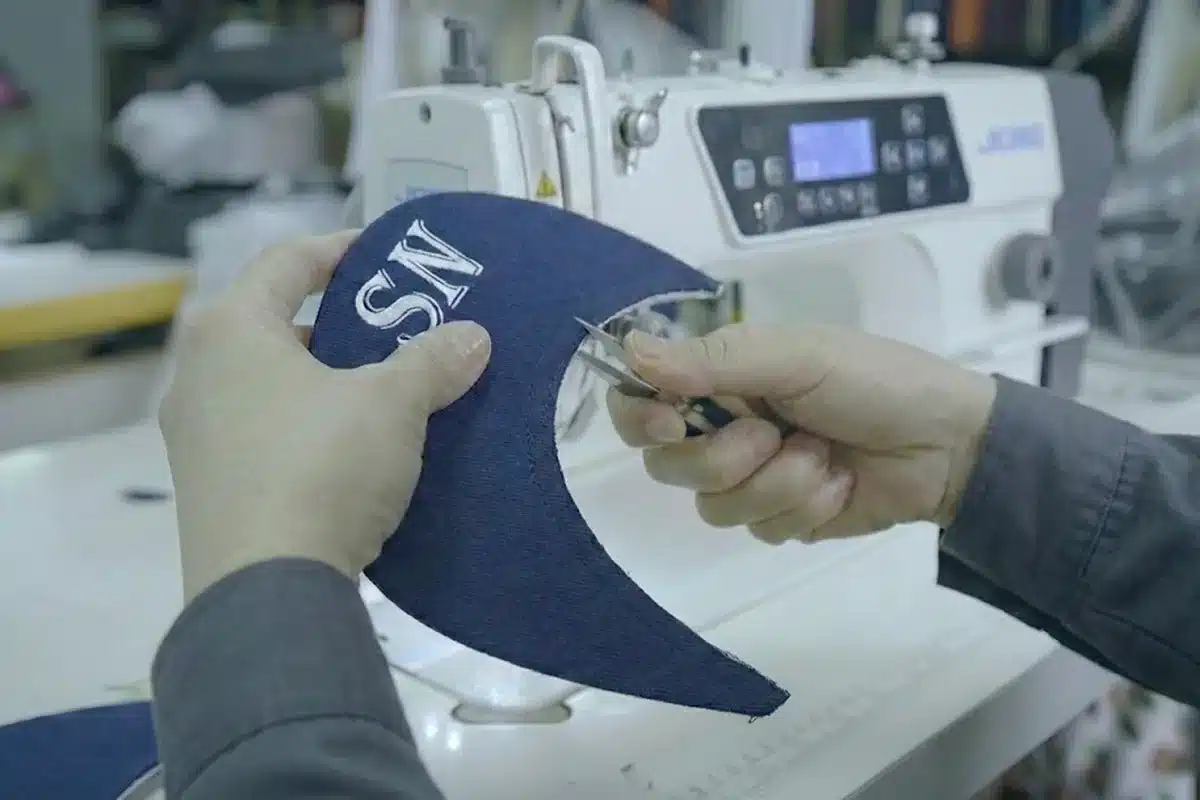 Operator trimming embroidery on a custom cap panel