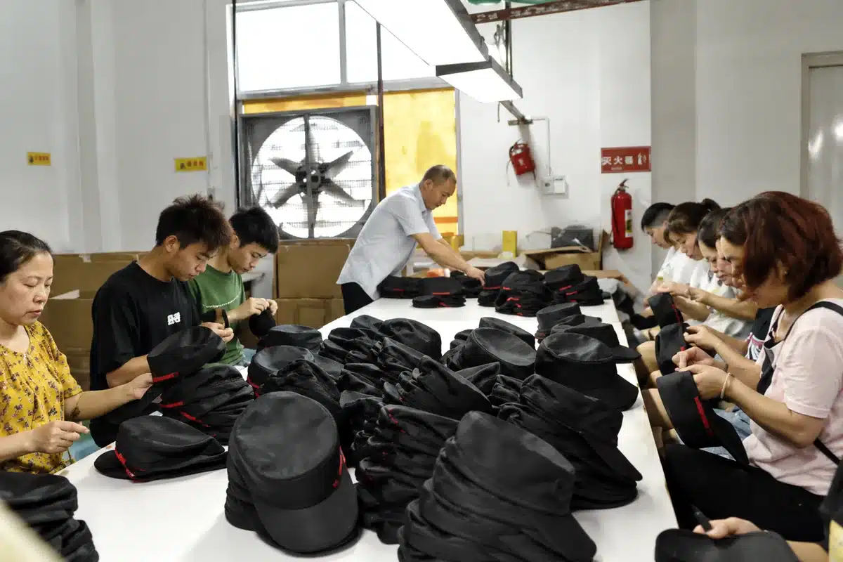 Workers inspecting and finishing black caps before packing