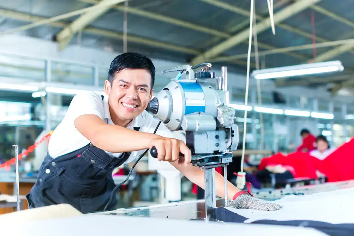 Worker operating cutting equipment in a hat production facility