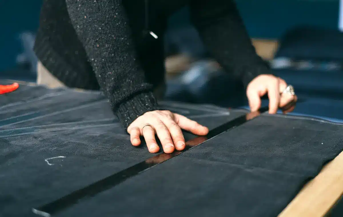 Person measuring dark fabric on a cutting table with a ruler