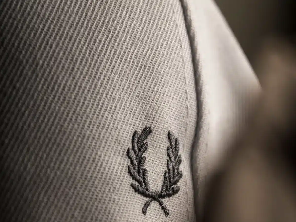 Close-up of embroidered olive-branch motif on the curved front of a fabric cap