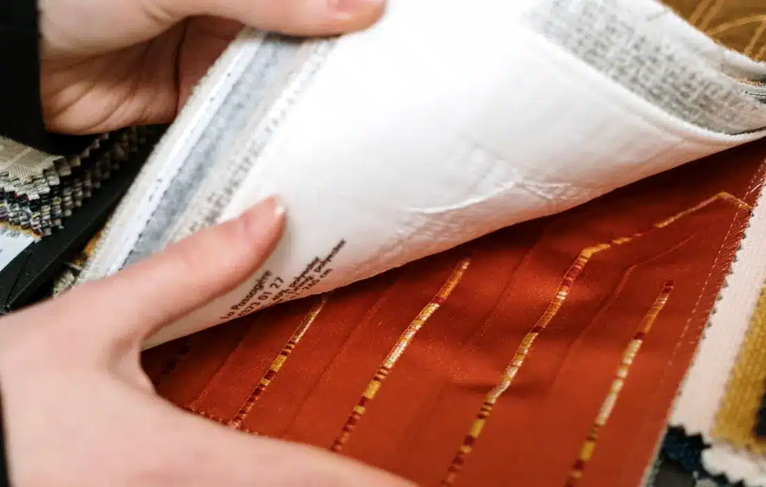 Hands comparing fabric swatches in a sample book